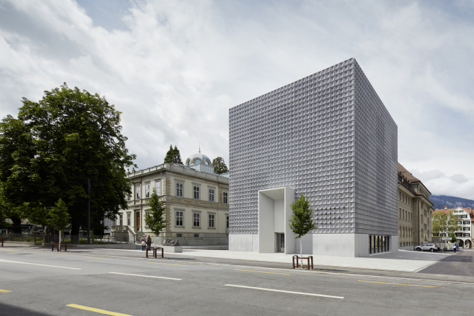 Art Museum (© Ralph Feiner) A modern, cubic building with a textured facade stands beside a traditional, ornate building under a cloudy sky