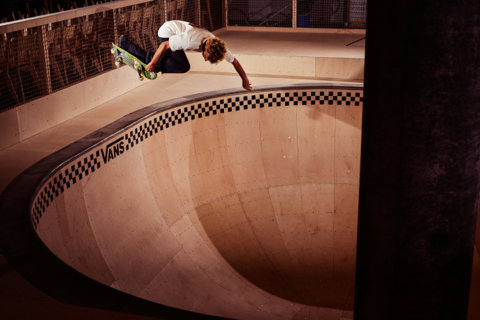 Laax freestyle academy (© Alan Maag) A skateboarder in mid-air performs a stylish trick above a deep, empty skate bowl with a Vans logo