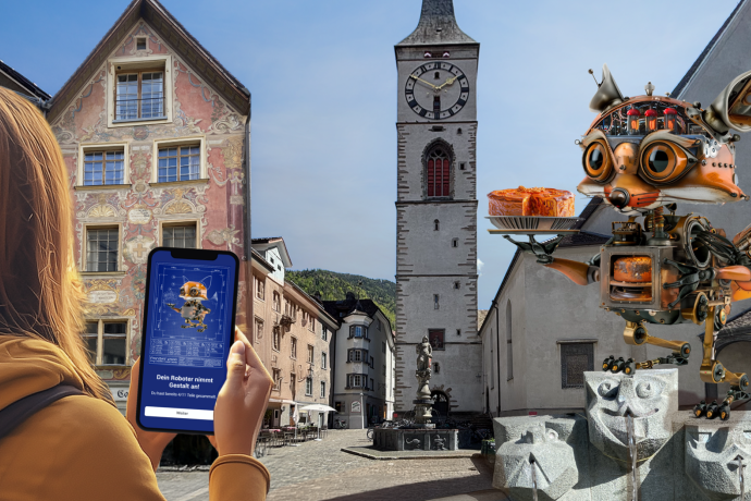 Foxtrail GO Chur (©Foxtrail) Eine Person hält ein Smartphone in der Hand, auf dem ein Roboterfuchs zu sehen ist, passend zu einer grossen Roboterfuchs-Skulptur, in Chur mit historischen Gebäuden und einem Uhrturm.